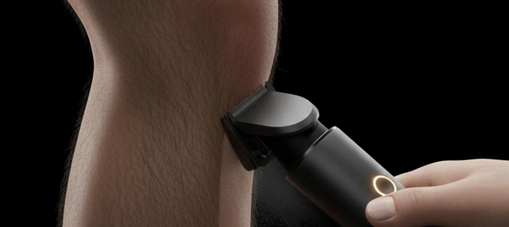 A hand holding a trimmer against a hairy leg